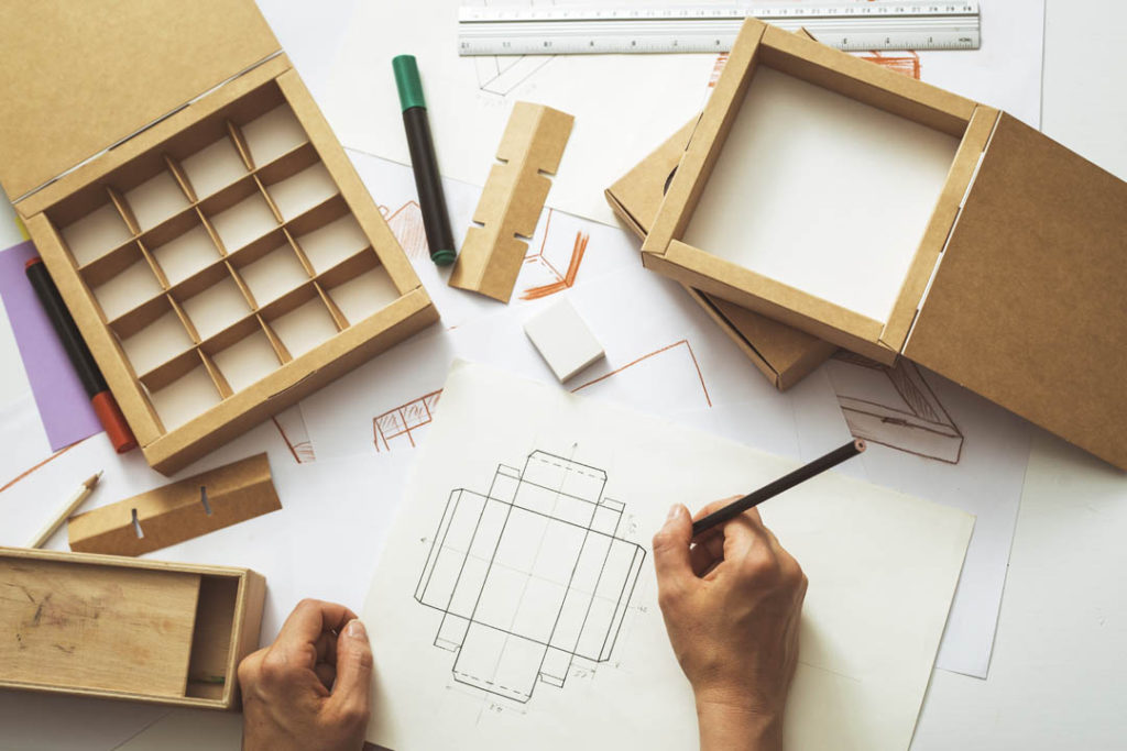 Ein Verpackungsexperte von Tillmann Verpackungen zeichnet den Entwurf einer Individualverpackung auf ein Blatt Papier